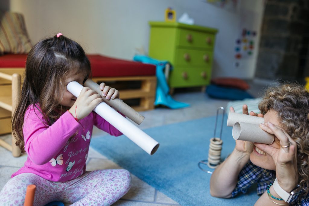 Una bimba e sua mamma giocano con dei tubi di carta