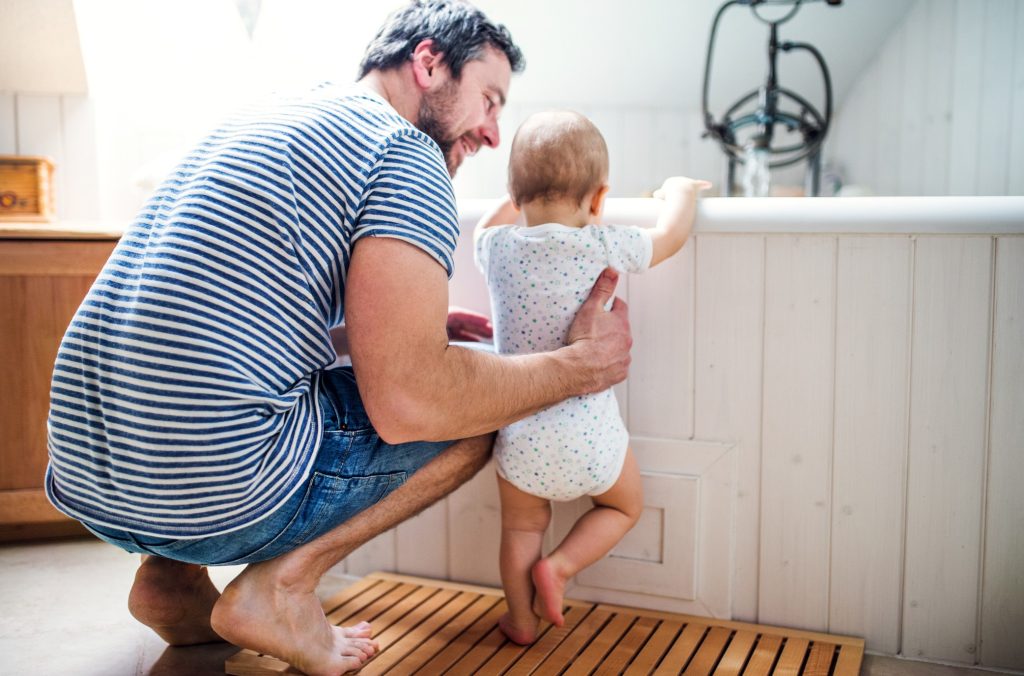 Un papà avvicina un bimbo piccolo alla vasca per il bagnetto