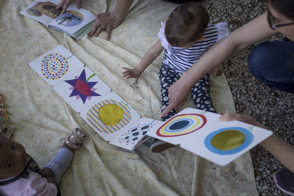 Adulto indica immagini su un libro illustrato a un bimbo