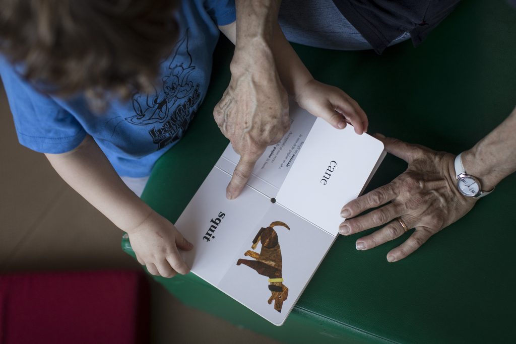Adulto indica parole scritte su un libro illustrato a un bimbo