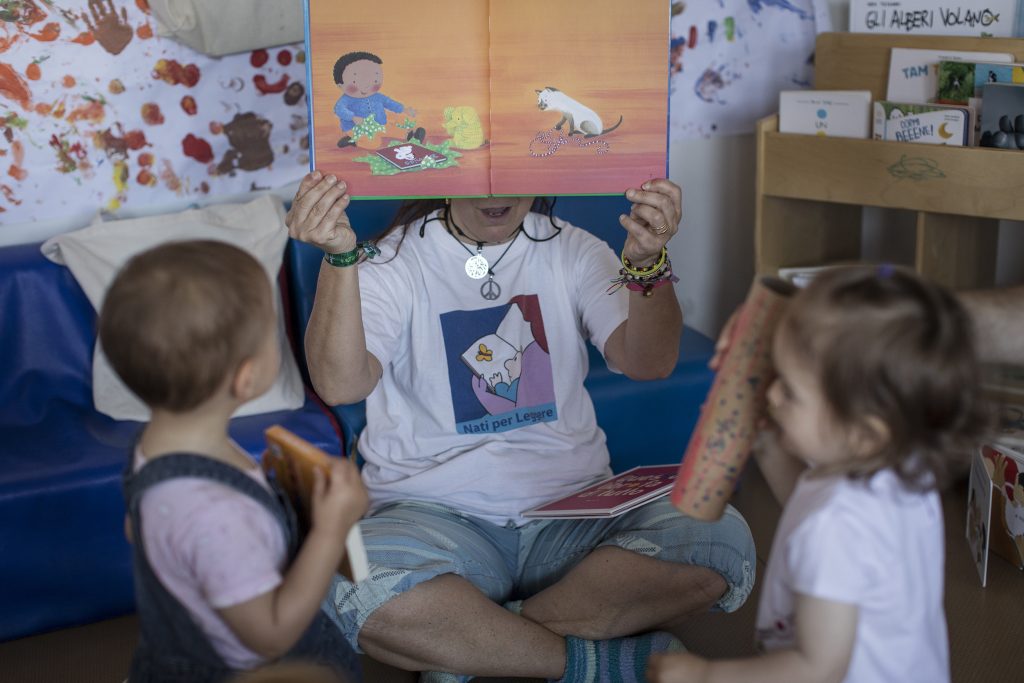 Formatrice mostra libri illustrati a bimbi e bimbe