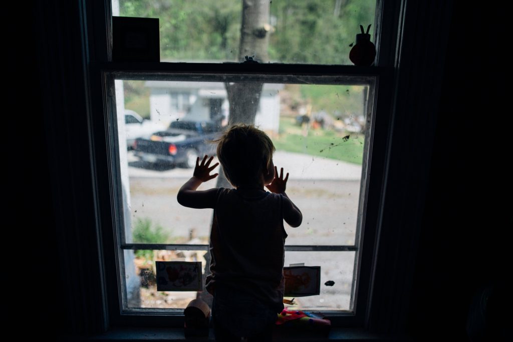 un bambino si annoia guardando fuori dalla finestra