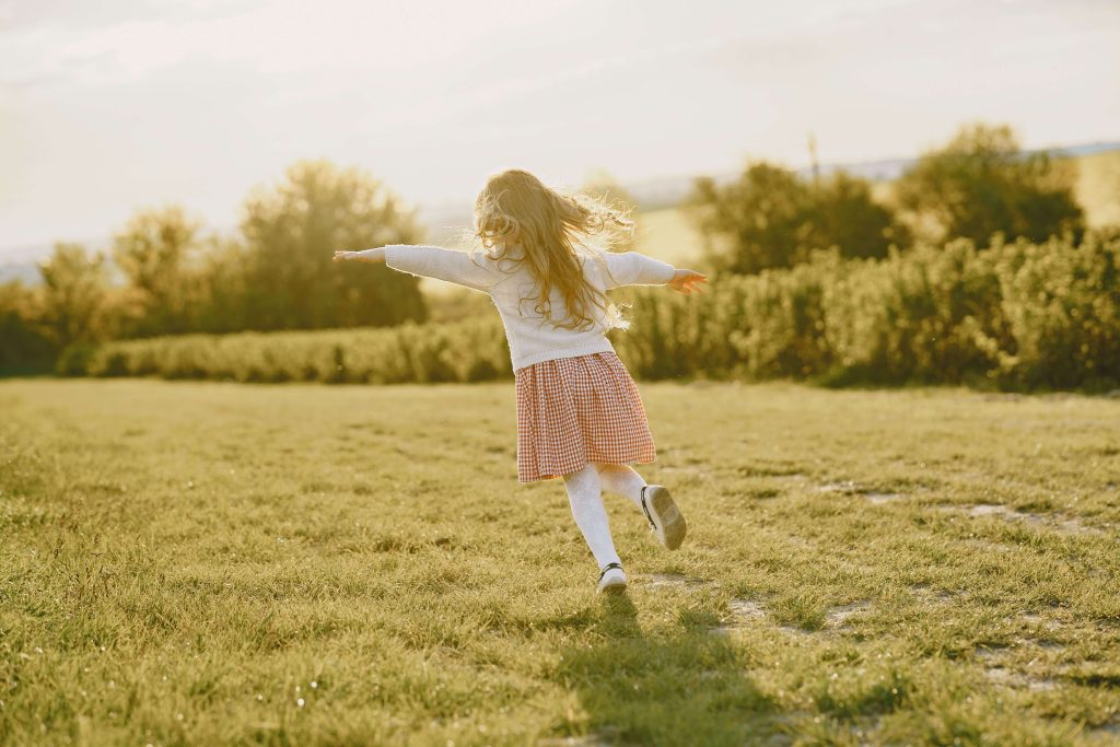 bambina corre spensierata su un prato