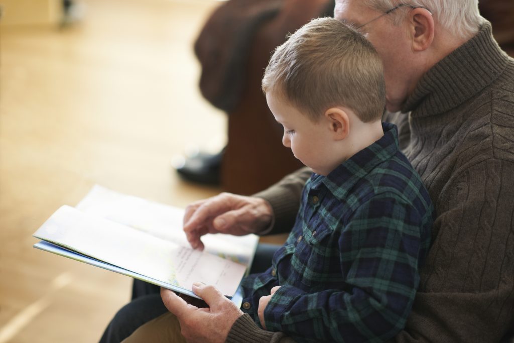 Un nonno e un bambino sfogliano insieme un libro.