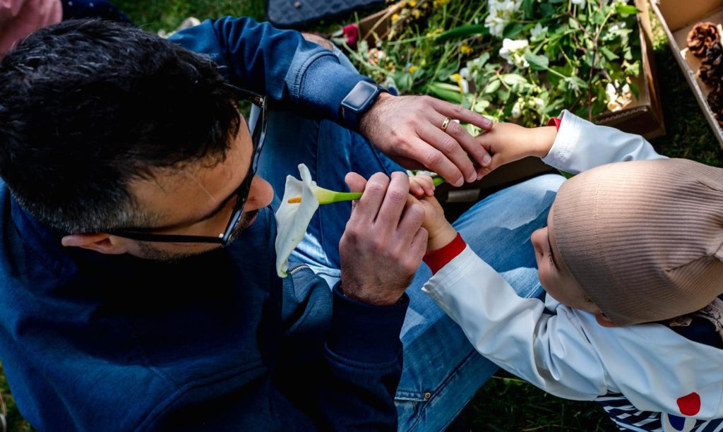 Un adulto e un bambino osservano insieme un fiore, nominando ciò che cattura lo sguardo